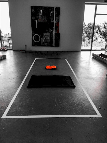 Die Vorbereitung „10/3“ am Vortag. Mitten im Raum wurde ein 4 m langer und 1,5 m breiter Rechteck auf dem Boden aufgeklebt. In dessen Mitte wurde ein 4 m langer und 1,5 breiter gefalteter schwarzer Stoff und ein genauso sorgfältig gefaltetes orangenes Kleid platziert. In der Ecke des Raumes erfolgte der Aufbau einer für die Aufnahme der gesamte Performance vorbereiteten Kamera.