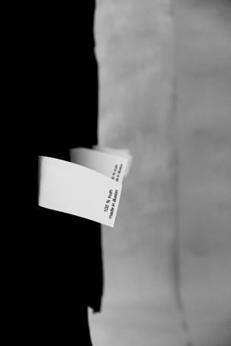 Installation aus in 2 parallel zueinander mitten im Raum an 0,1 mm dünnen Metallseilen von der Decke aufgehängten Reihen. Jede Reihe besteht aus 100 schwarzen Stoffbahnen an den Seiten zusammengenäht, breite 60 cm und höhe 77 cm, jeweils an einer 1 m langen Gewindestange im Abstand von 5 cm hintereinander in Schulterhöhe aufgehängt. Jede Stoffbahn ist mit einem Etikett versehen. Die 100 links hängende, das Hinweisetikett rechts mit der Aufschrift 100% truth made in illusion. Die 100 rechts hängende, das Hinweisetikett links mit der Aufschrift 100% illusion made in lie